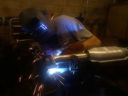 A welder working on an exhaust pipe