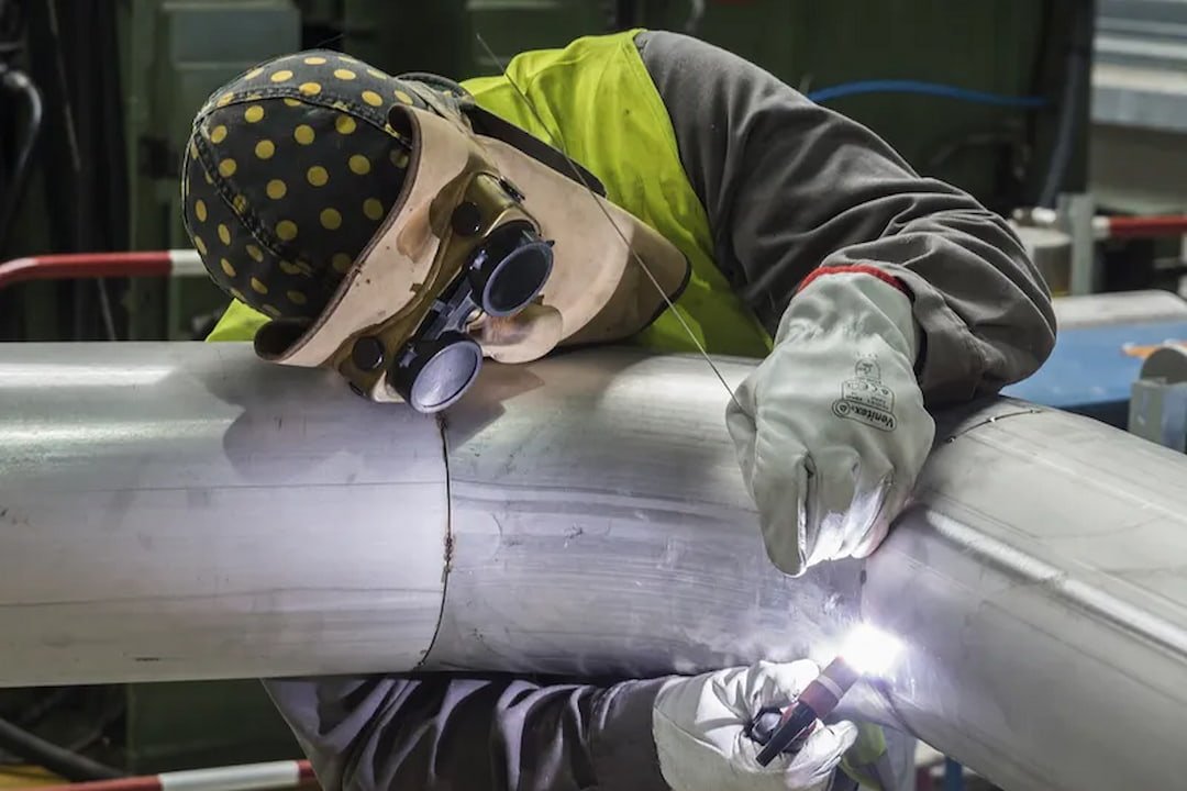 a welder working on aluminum pipe