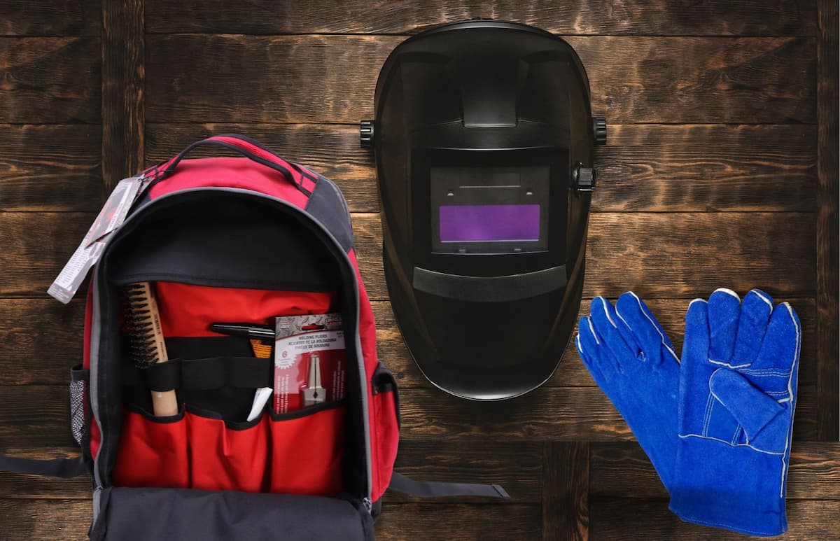 Welding backpack, helmet and gloves on the wooden surface